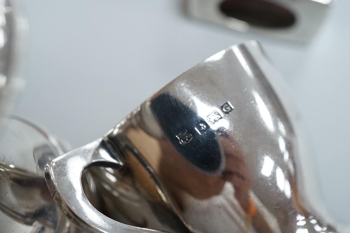 Four assorted silver condiments including a Victorian bun salt and a late Victorian pepper mill, together with a small silver bowl, a silver matchbox sleeve and a small silver two handled cup.